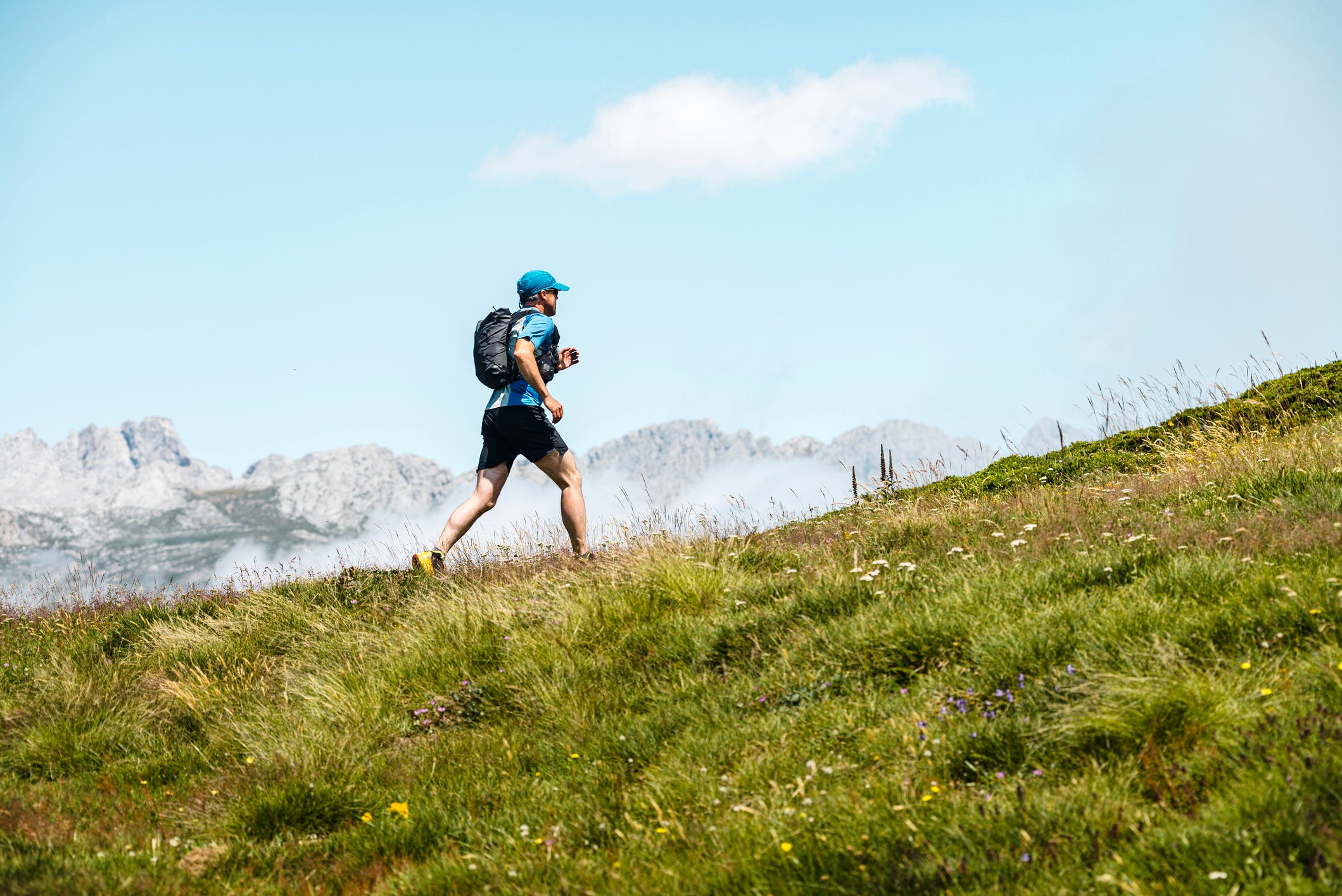 Spain, Castille and Leon, Santa Marina de Valdeon, Close view of a trail runner running in the meadows close to Collado Jermoso, Runner, Workout, Mountains, Trail Run (Spain, Castille and Leon, Santa Marina de Valdeon, Close view of a trail runner run