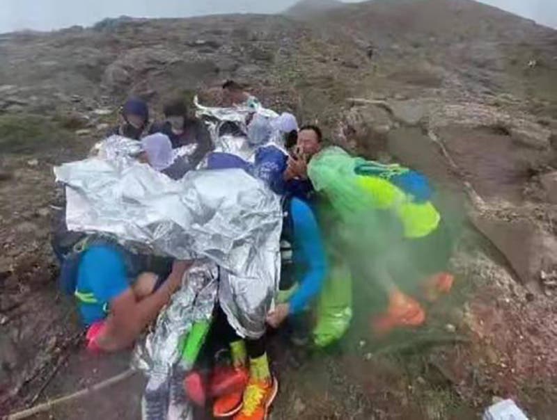 Runners huddle together under space blankets