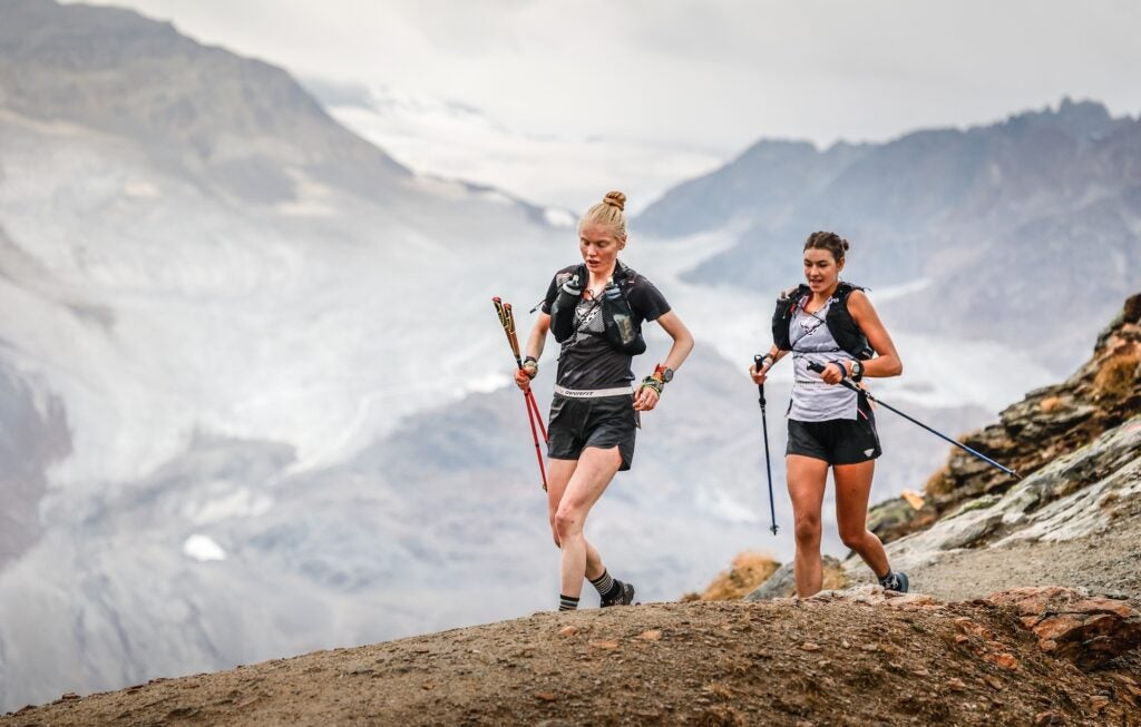 Two top woman run along a ridge in the Alps