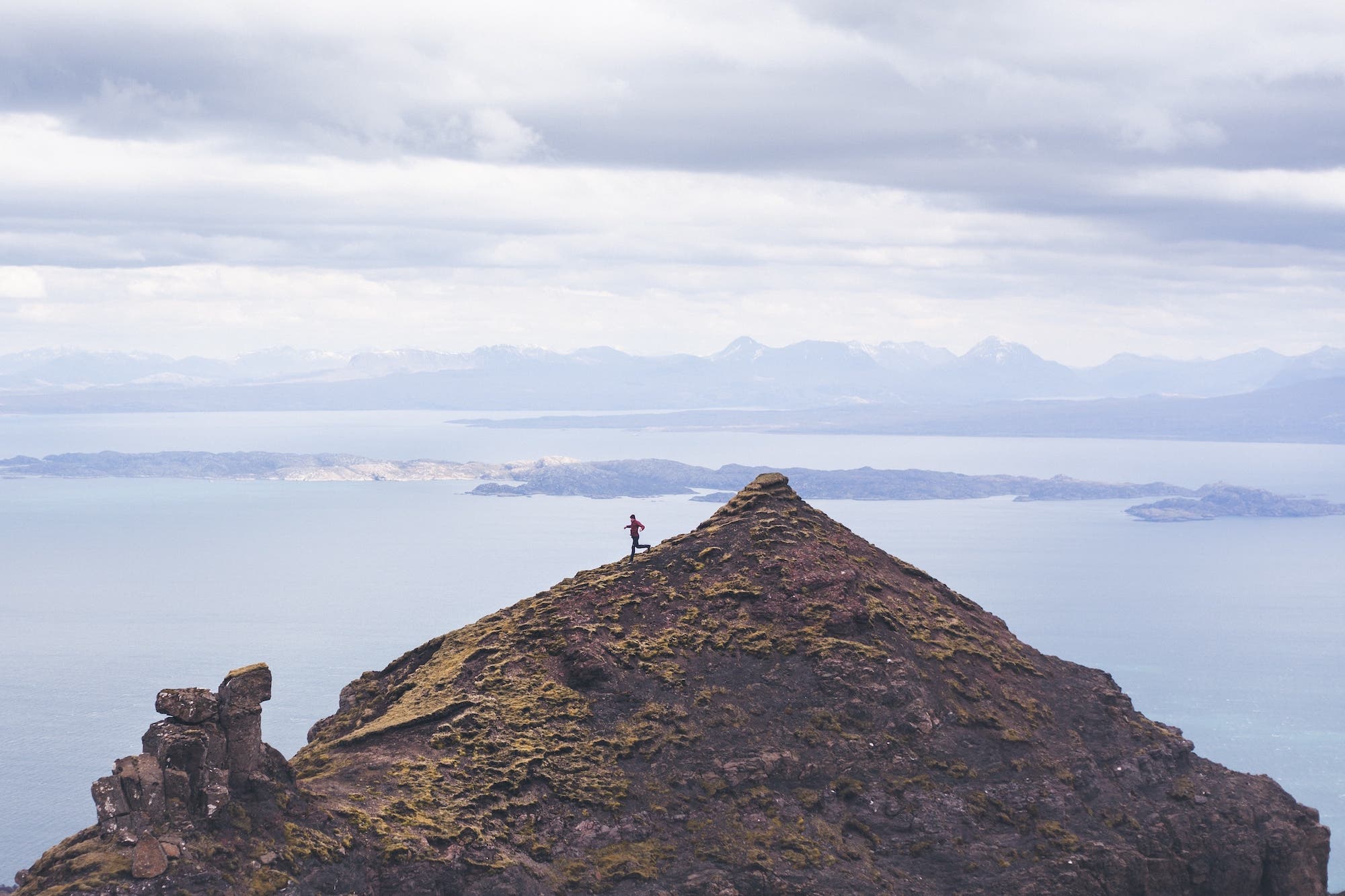 a person runs on the top of a mountain that overlooks the ocean