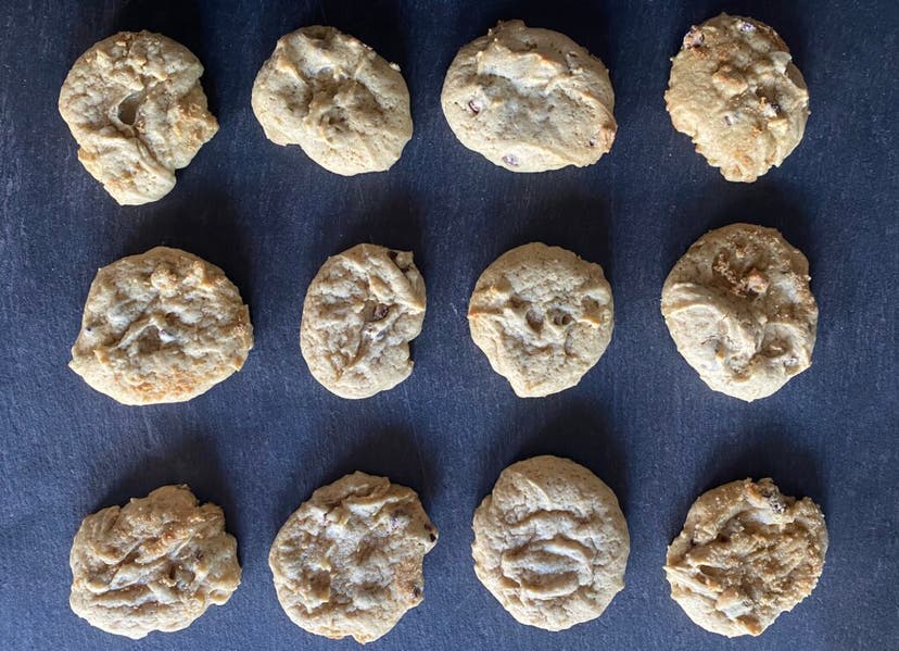 A baking rack with a dozen chocolate chip cookies on the a pan.