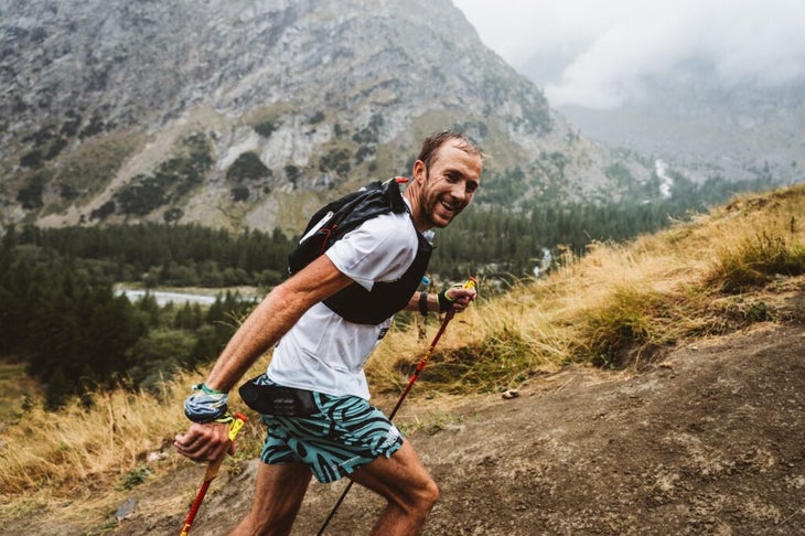 A man in a white shirt is hiking up a hill