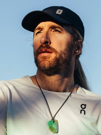 Portait of Friedly in a black hat and white shirt with a necklace