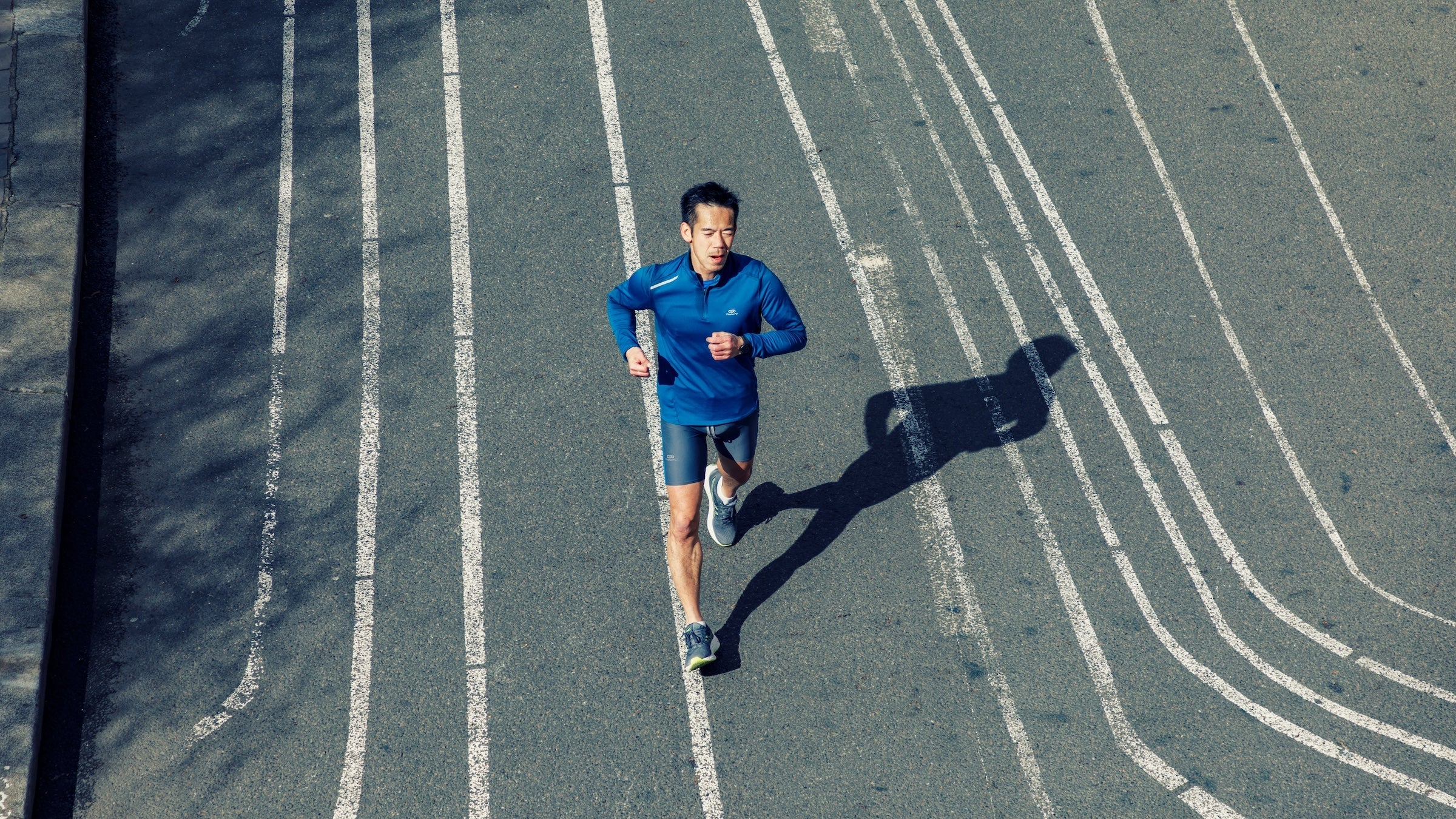 A man runs along strips of white paint on a road