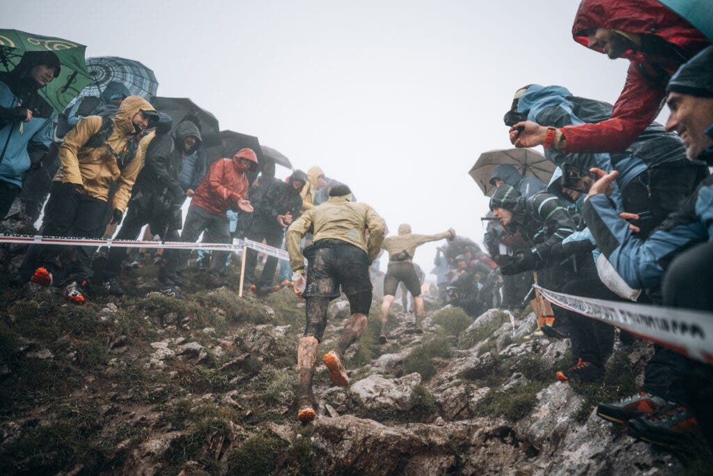 Two men climb up a muddy trail