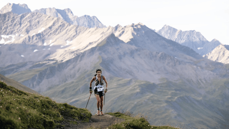 Ruth Croft ascending with dramatic alpine passes behind her.