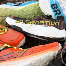 Pile of shoes including the Saucony Peregrine 16, Brooks Cascadia Elite, La Sportiva Progio Pro, and Zegama and Pegasus Trail by Nike