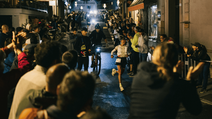 Photo of Blandine L’Hirondel running through a dense crowd of people in an alpine village at night.