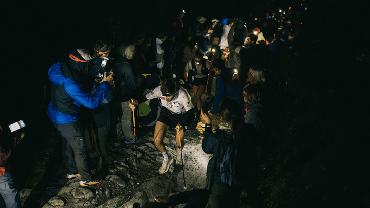 Photo of Moises Jimenez alongside Lucy Bartholomew climbing thorugh a tunnel of people in the night.